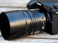 Angle on a black Lumix camera with a large zoom lens attachment on it.