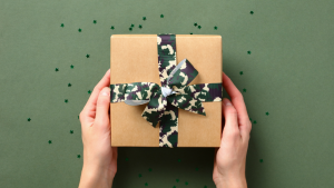 Hands holding a box with camouflage wrapping against a green background