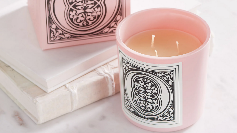 An image of the Otho candle in bright pink alongside a stack of books.