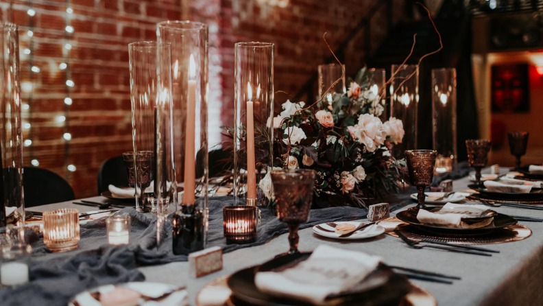 Elegant wedding guest table with candles, plates, and flatware on top.