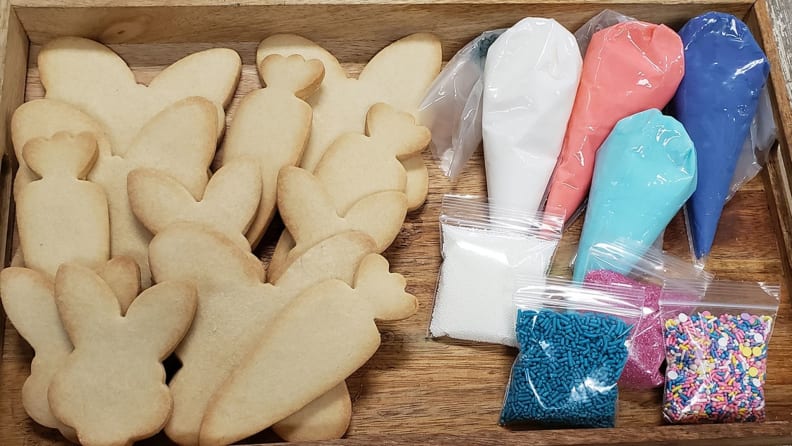 Plain sugar cookies in various Easter-themed shapes accompanied by plastic tubes of pastel-colored icing and sprinkles.