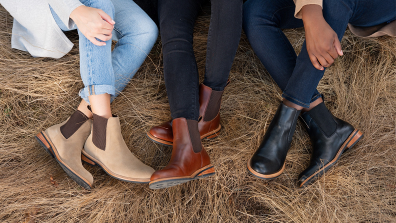 Several people wearing Nisolo boots while laying on a hay bail.