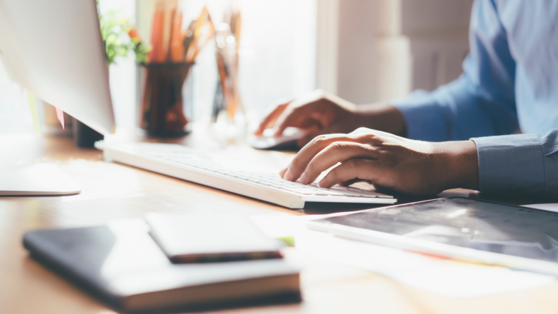 Person typing on keyboard at desk.