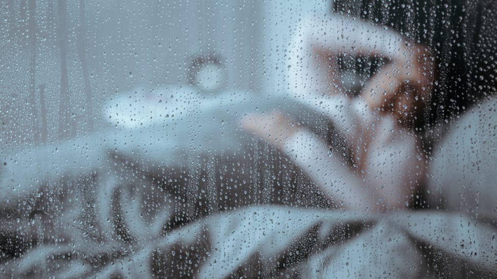 Restless woman in bed in front of rainy window
