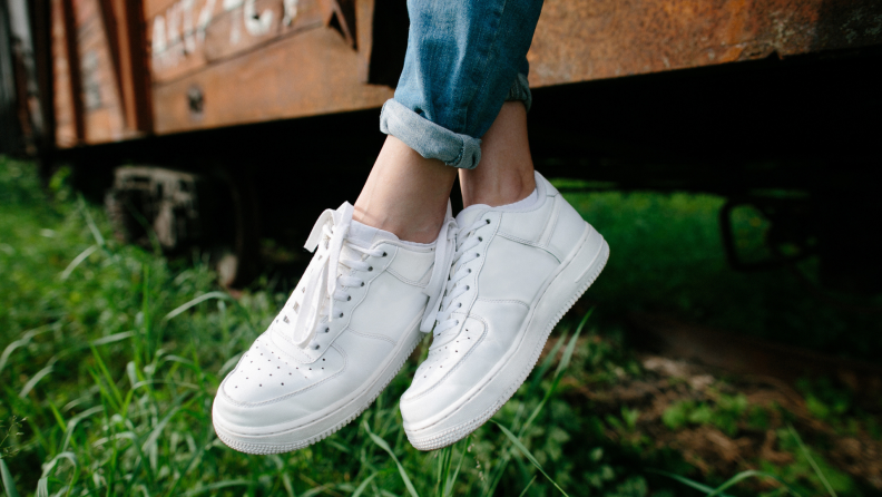 Woman sitting with white sneakers paired with jeans