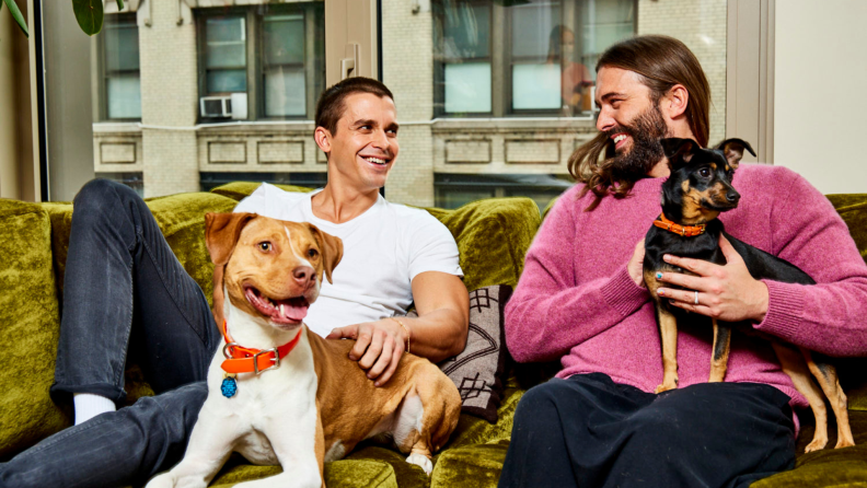 Antoni and Jonathan sitting on a couch with their pets.