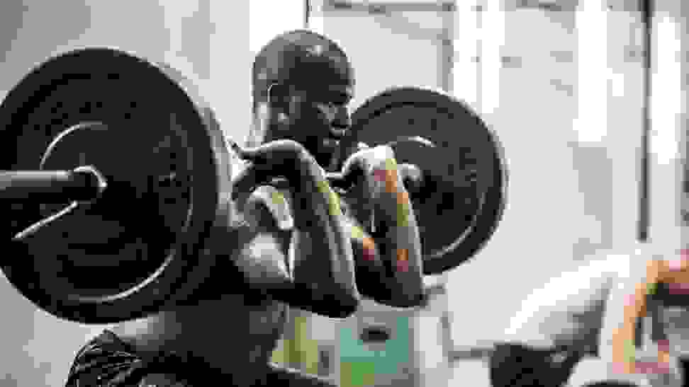 An athlete performs squats with a large barbell.