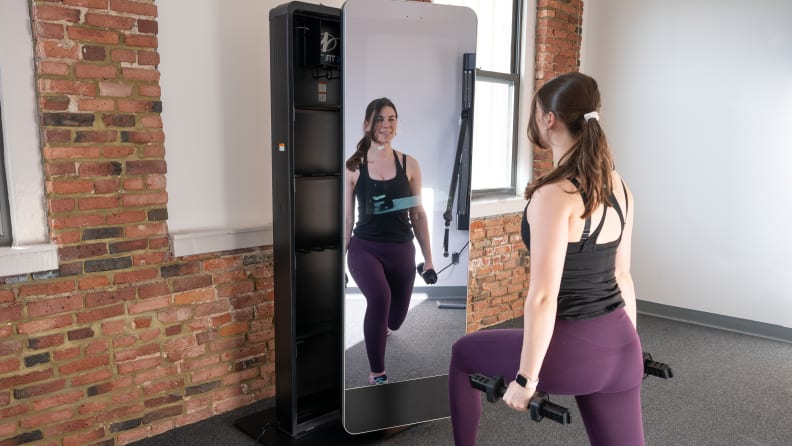 A woman doing lunges with dumbbells with the NordicTrack Vault.