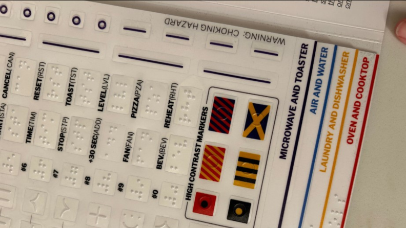 A close-up view of the GE Appliances Access Kit, with four tabbed sheets of braille and phrases in written English on each tab.