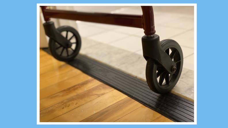 Koła chodzika wykorzystujące gumową rampę progową Rampit Empower Series do przetaczania się z drewnianej podłogi na podwyższoną podłogę w kuchni.