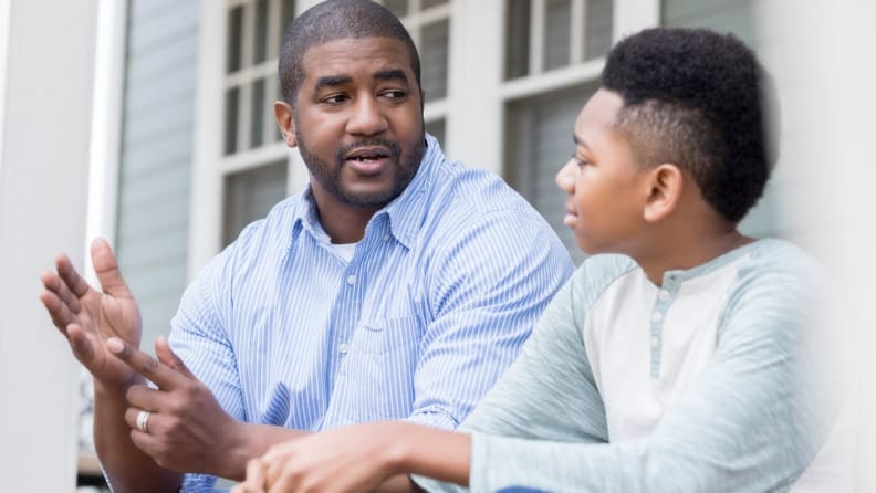 A Black man talks with his teenage son.
