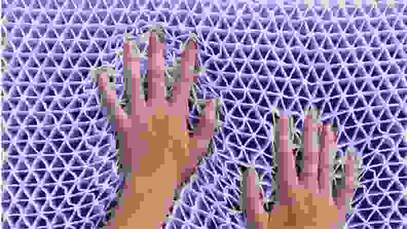 a pair of hands press into the purple polymer grid used in the Purple Pillow