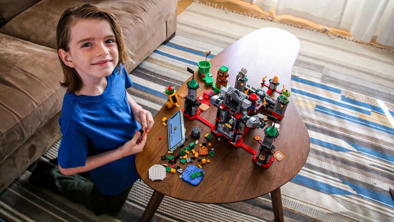 A child looks up proudly as he builds his Lego set.