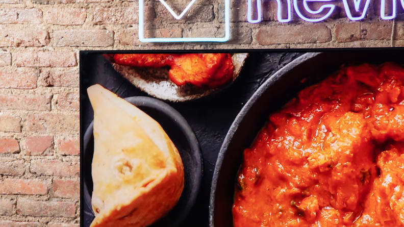 A TCL QM8 LED TV showing food being cooked onscreen with vibrant colors.