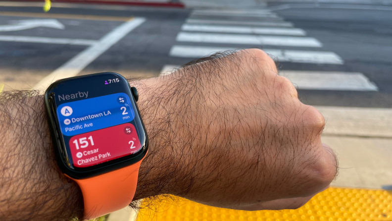 A person checks an Apple Watch fastened to their wrist featuring the Transit app.