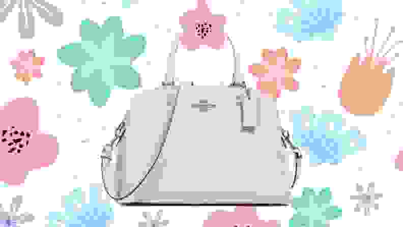 A white Coach shoulder bag against a floral background.