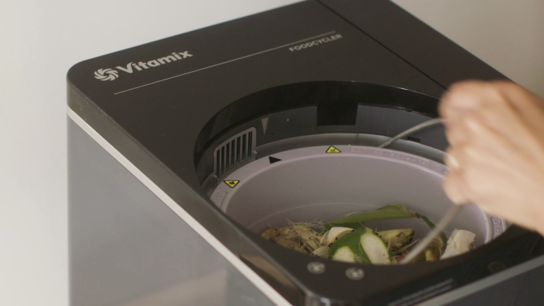 Person putting veggie scraps in Vitamix FoodCycler