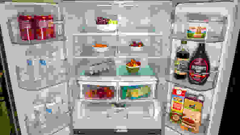 A close-up of the interior of the LG LFCS22520S French-door fridge, with both its doors open. The compartments and bins are filled with food, for scale.