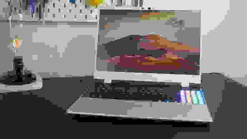 The Framework Laptop 16 on a black desk next to a lamp.