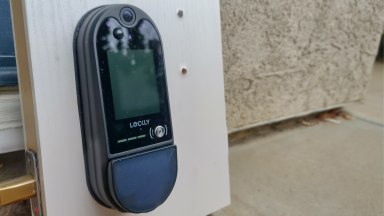The Lockly Vision Elite smart lock leans on the wall of a house before installation.