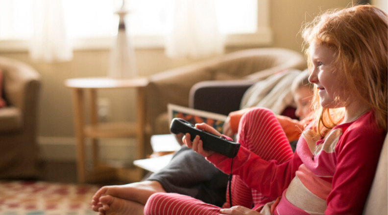 A young child watches TV on the couch