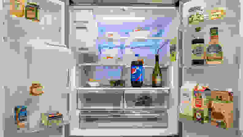 The interior of the fridge, stocked with food items for scale
