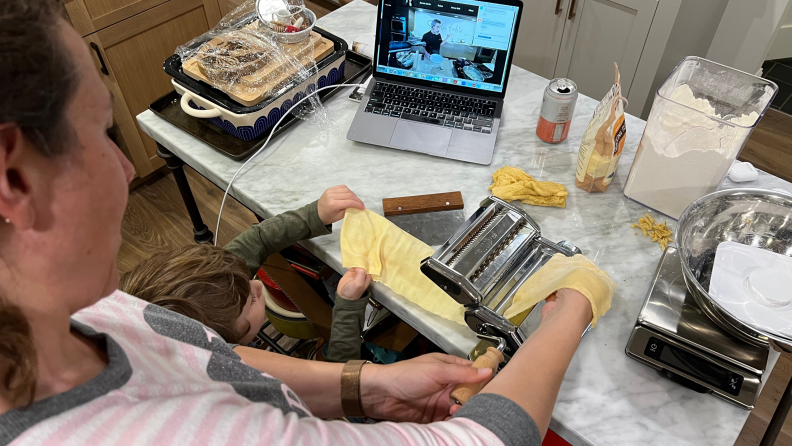 A woman and child make homemade pasta while watching the Sur La Table chef instructor on the computer.