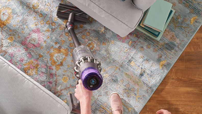 A person vacuums their carpet with a Dyson V11 Torque Drive.