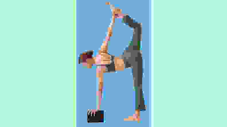 A person performing a yoga pose while holding onto a yoga block.