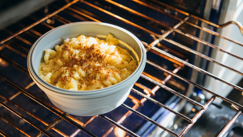 In a lit oven, there's a freshly baked cake inside a Stojo bowl.