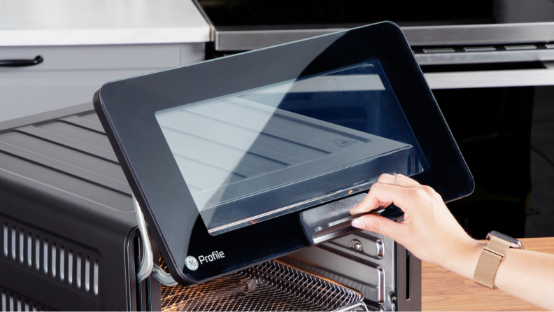 A hand holding up the GE Profile smart oven's door.