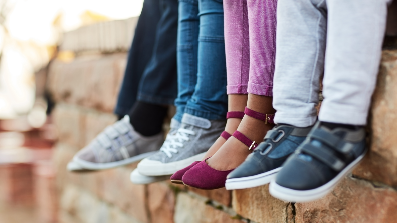 Four pairs of children's feet and legs wearing different shoes