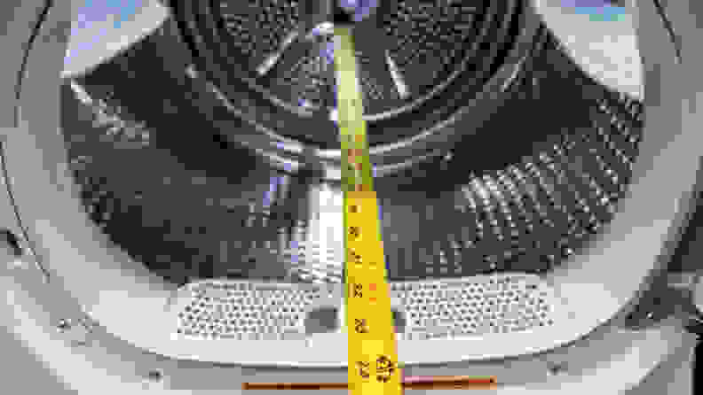 A yellow measuring tape stretches into the drum of a dryer showing it measures 24 inches