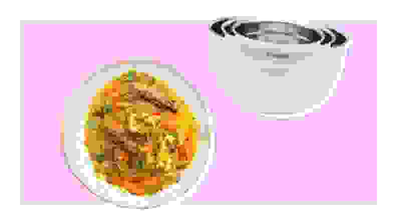 Plate of fish stew and pile of stainless steel mixing bowls on purple background