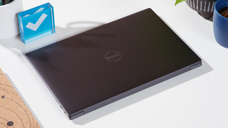 A closed dell xps 14 laptop with a slate grey finish on a white table