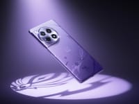 The back of the purple Genshin Impact edition OnePlus 12R smartphone floating while illuminated by a purple spotlight.