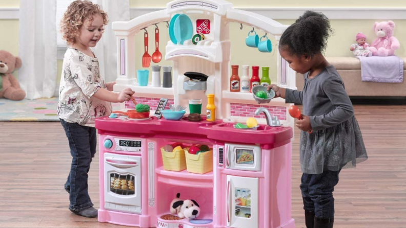 Two girls playing at a toy kitchen