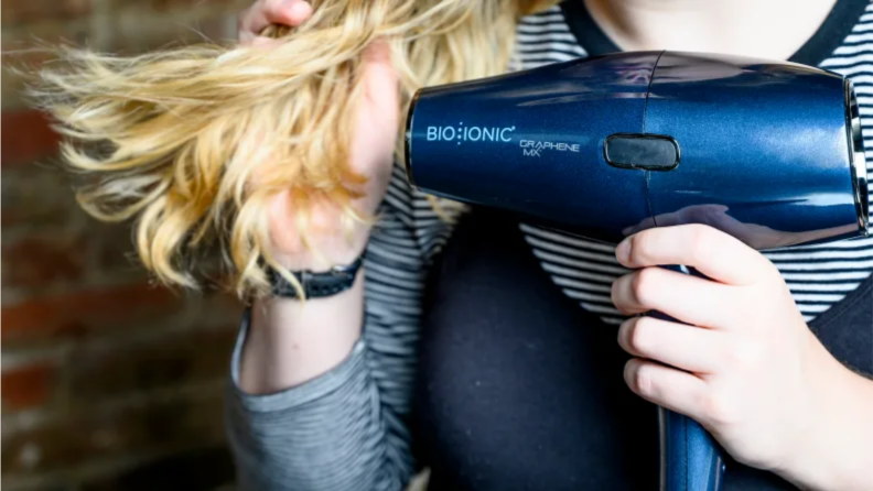 An image of a woman using a hair dryer.