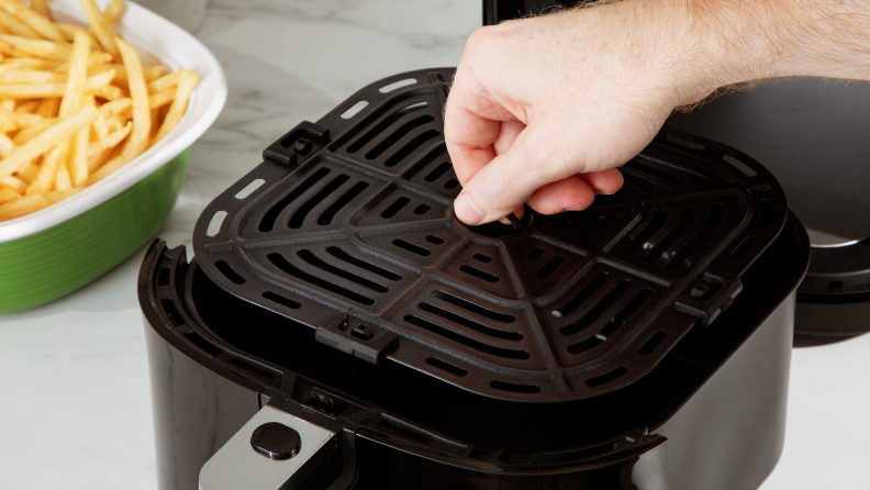 Person lifting up the removable wire rack from the inside of the sliding basket on the Proscenic T22 Air Fryer.