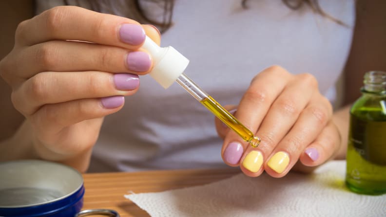 A closeup on a person's hands as they apply cuticle oil to their nails.