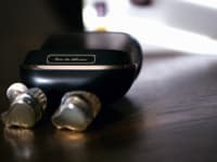 A pair of black and gold earbuds sit on a table
