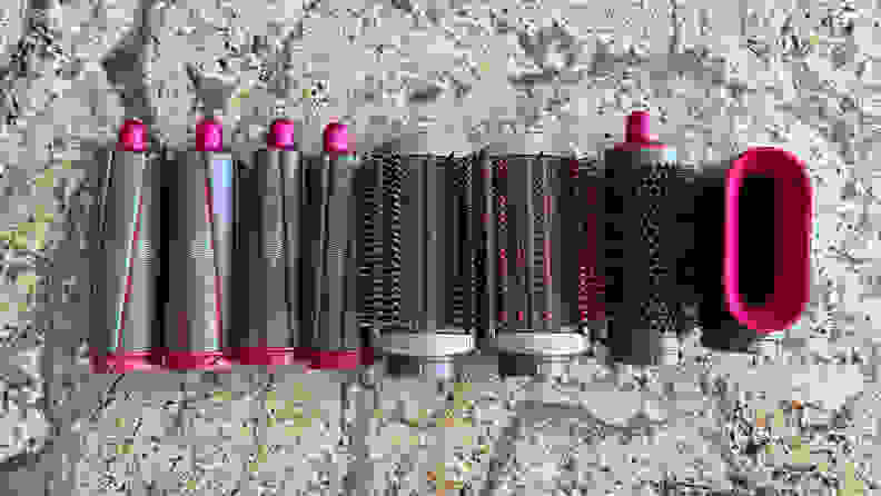 The Dyson Airwrap Styler attachments against a granite countertop. From left to right: the curling wands, the smoothing brushes, and the pre-styler dryer.