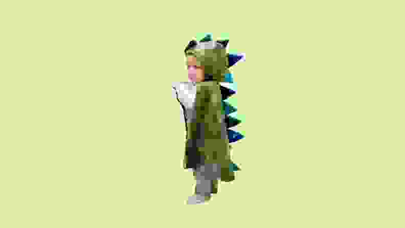 A toddler wearing a green dragon costume.