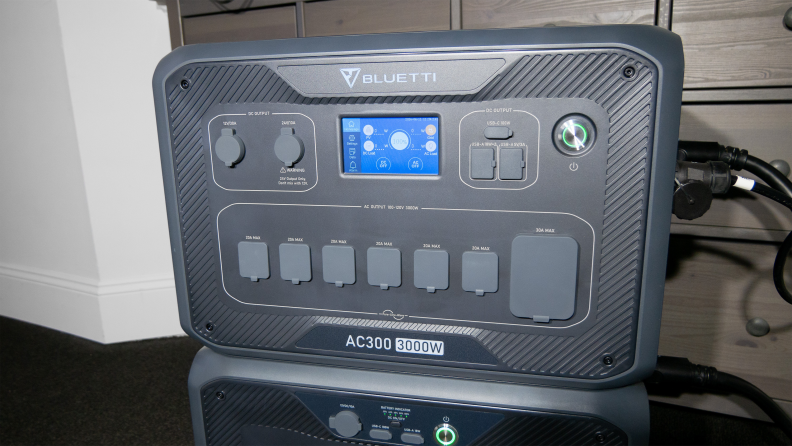 The Bluetti AC300+B300 appears next to a wall, with power cords attached.