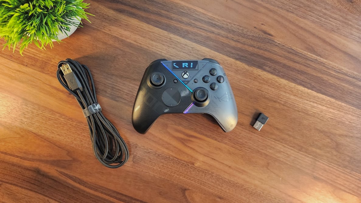Asus ROG Raikiri Pro controller sitting on top of wooden surface next to usb and power cord.