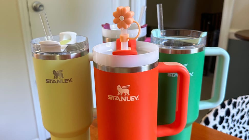 Four Stanley Quencher H2.0 Flowstate Tumblers of different colors sitting atop a table.