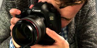 A photographer demonstrates a Canon DSLR camera.