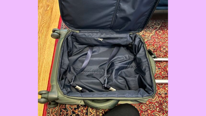 An image of a Lipault suitcase, open, on a carpeted floor.