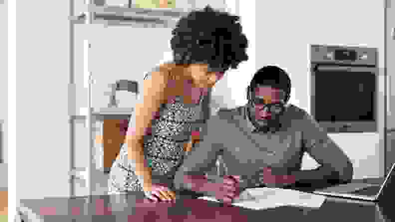Black couple looks at computer screen while in their kitchen