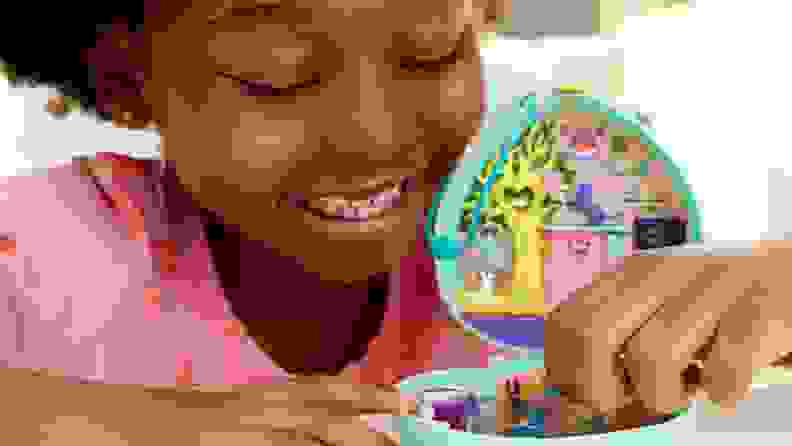 Young child playing with small Polly Pocket toy.